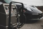 Krupni plan Idromatic Astra Vortex - Industrijski Parocistac (220°C, 3 operatera, dizel, 48kW) sa komandama i crijevom; elegantan crni auto u pozadini.