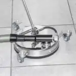 Mosmatic FL-SAR 300, čistač površina sa automatskim odvodnjavanjem, leži na pločicama. Ima četiri kotača za lako kretanje i crijevo za efikasno usisavanje.