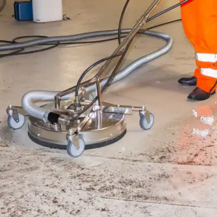 Noseći narandžaste zaštitne pantalone, neko koristi Mosmatic FL-SAR 520 povrsinskog cistaca sa kružnom četkom i crevom da efikasno očisti mokri pod.