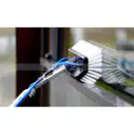 Detaljni prikaz četke na teleskopskom štapu dok nežno uklanja prljavštinu sa stakla.