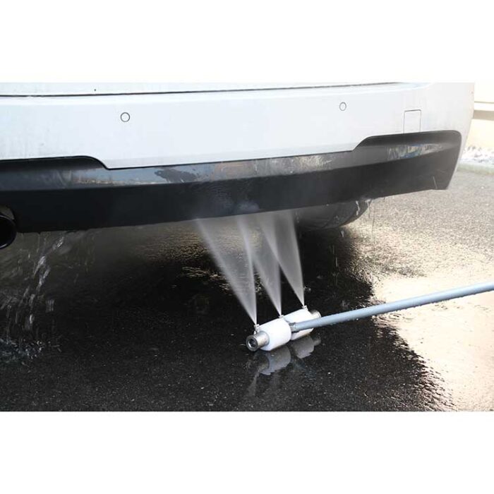 Zadnji branik bijelog automobila se čisti mlazom vode pod visokim pritiskom od 180 bara ST-245, koji stručno pere donju stranu na mokrom kolovozu.