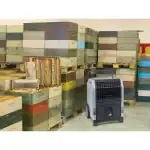 Mašina za isušivanje vlage BIEMMEDUE DR100 (100L/h) na podu ispred šarenih košnica, drvenih paleta i saća u magacinu.