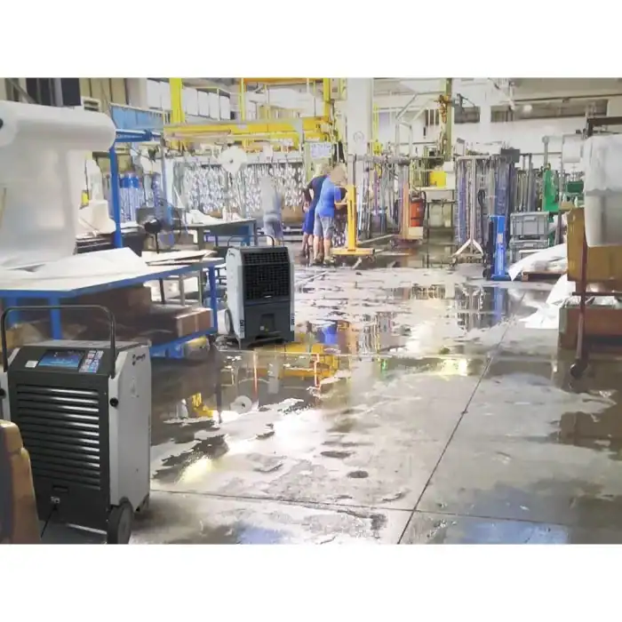Velika industrijska hala sa mokrim podom, dva BIEMMEDUE DR70 odvlaživača i radnik u plavom pored opreme i polica.