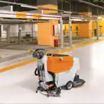 CHANCEE XMD50 samohodna mašina za pranje podova stoji na sjajnom podu parkinga sa narandžastim stubovima i platformama.