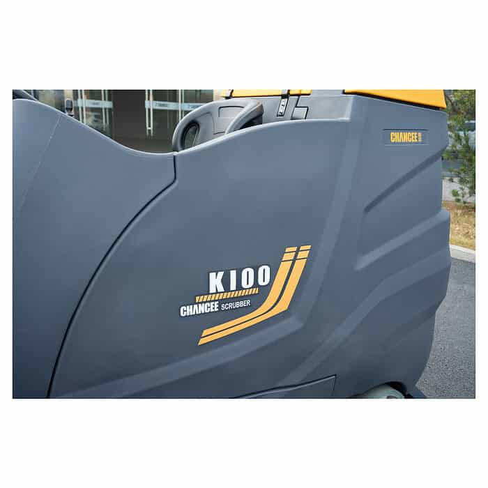 Izbliza sivi i žuti CHANCEE K100 za pranje podova (10000m², 1000mm, 5h baterija, 36V, 3 god garancije) ispred ulaza u zgradu.