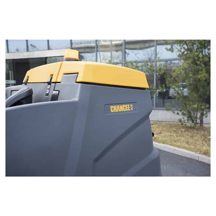 U krupnom planu CHANCEE K100, sivo-žuta mašina za čišćenje podova, parking ispred zgrade sa staklima i drvetom.