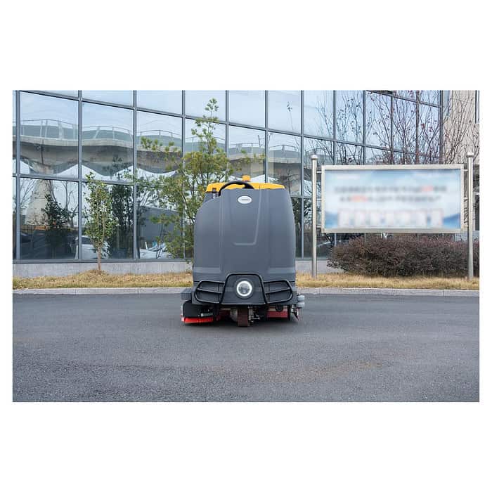 Mašina za čišćenje podova CHANCEE K100 stoji nepomično na asfaltu ispred staklene zgrade, sa drvećem i mutnim znakom iza nje.