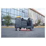 Čistač podova CHANCEE K100 sa vozačem je parkiran ispred moderne staklene zgrade, a iza njega se vide drveće i grmlje.