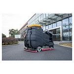 Na asfaltu ispred moderne staklene zgrade stoji CHANCEE K100 mašina (10000m², 36V), okružena žbunjem i drvećem.