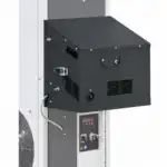 Detaljan snimak industrijske mašine prikazuje crnu metalnu kutiju sa ručkom, ventilima i tasterima ispod. Veliki ventilator je delimično vidljiv sa leve strane.