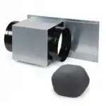 Na beloj podlozi leži pravougaoni metalni HVAC spoj sa crnim okruglim krajevima pored okruglog crnog sunđerastog filtera.