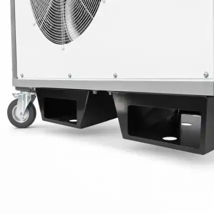 Prikaz donjeg ugla industrijske mašine sa velikim ventilatorom, točkićem i dva crna džepa za viljuškar; vidi se i deo metalnog kućišta sa šrafovima.